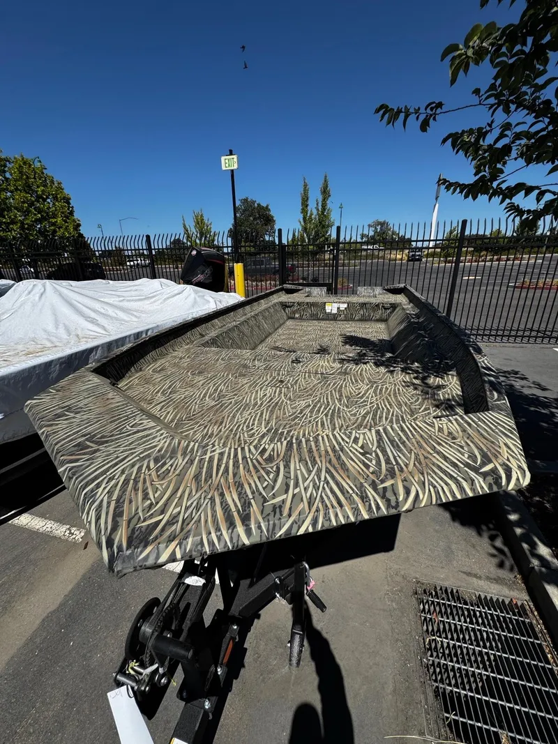 Slide: The Image of 2025 Tracker GRIZZLY 2072 Utility boat with camouflage pattern in a parking lot. - 2