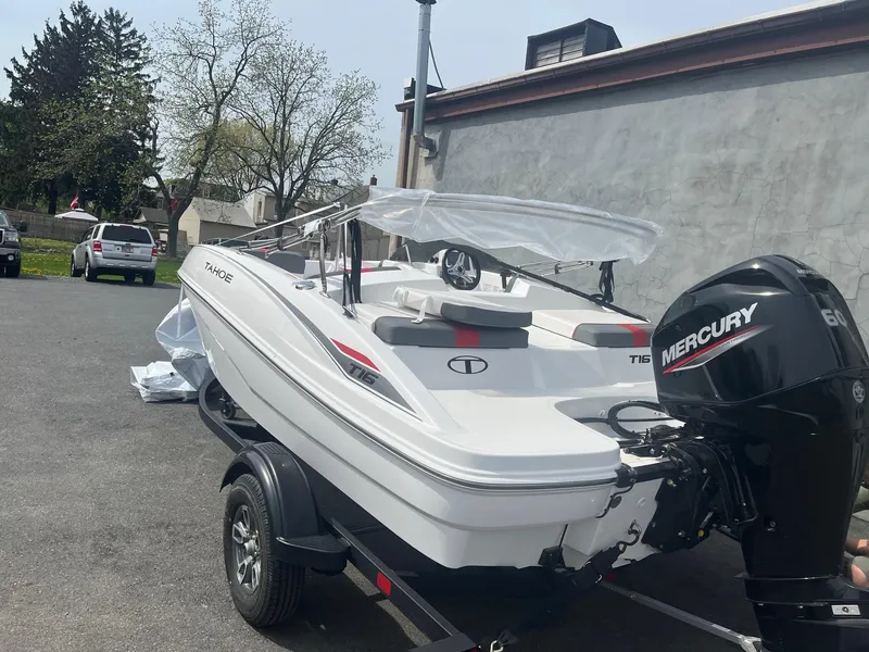 Slide: The Image of 2025 Tahoe T16 boat with Mercury engine on trailer, parked outdoors. - 1