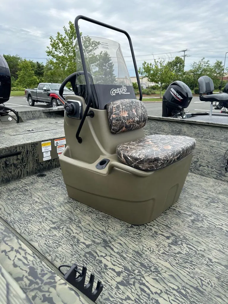 Slide: The Image of 2025 Tracker Grizzly 2072 CC boat with camo seating and console, parked outdoors. - 2
