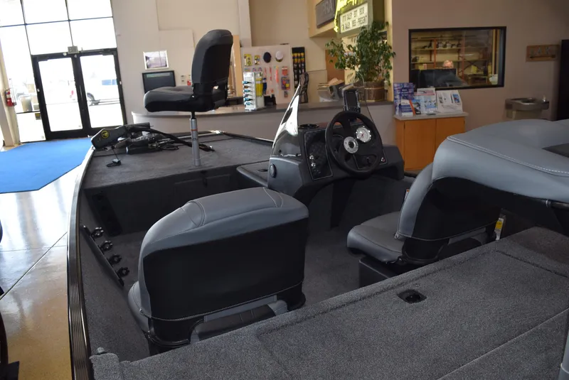 Slide: The Image of 2025 Tracker Bass Tracker Classic XL interior with seating and steering console in showroom. - 2