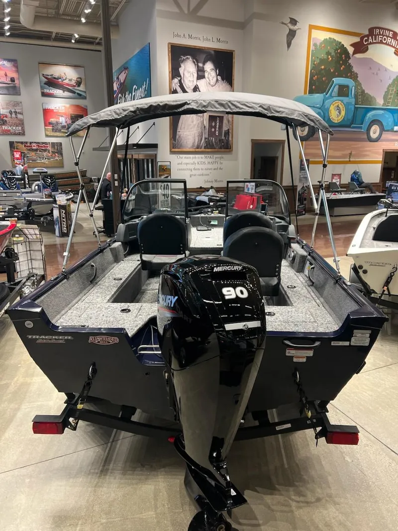 Slide: The Image of 2025 Tracker Pro Guide V-16 WT boat with Mercury 90 engine in showroom. - 2