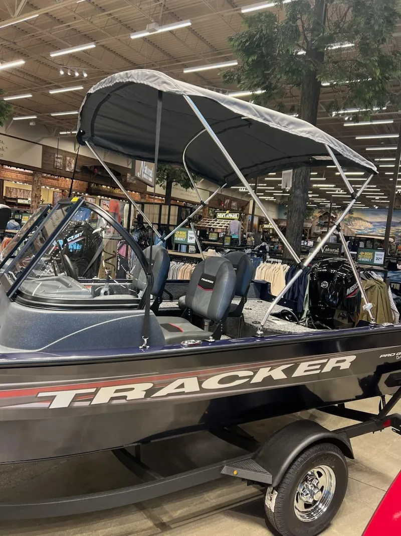 Slide: The Image of 2025 Tracker Pro Guide V-16 WT boat displayed indoors with canopy. - 3
