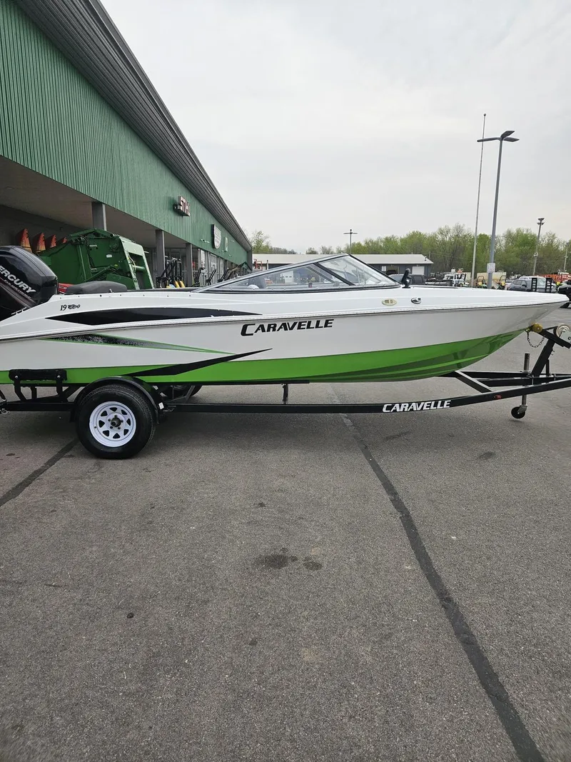 Slide: The Image of 2015 Caravelle 19EBo boat with green and white design on a trailer. - 0