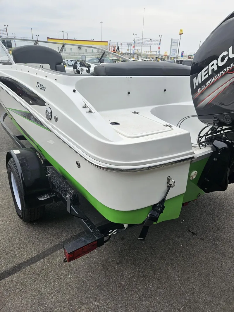Slide: The Image of 2015 Caravelle 19EBo boat with Mercury engine, green and white design, on trailer. - 2