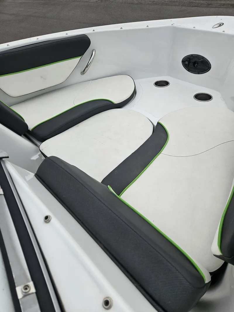 Slide: The Image of 2015 Caravelle 19EBo boat interior with white and black seating, green accents, and cup holders. - 5