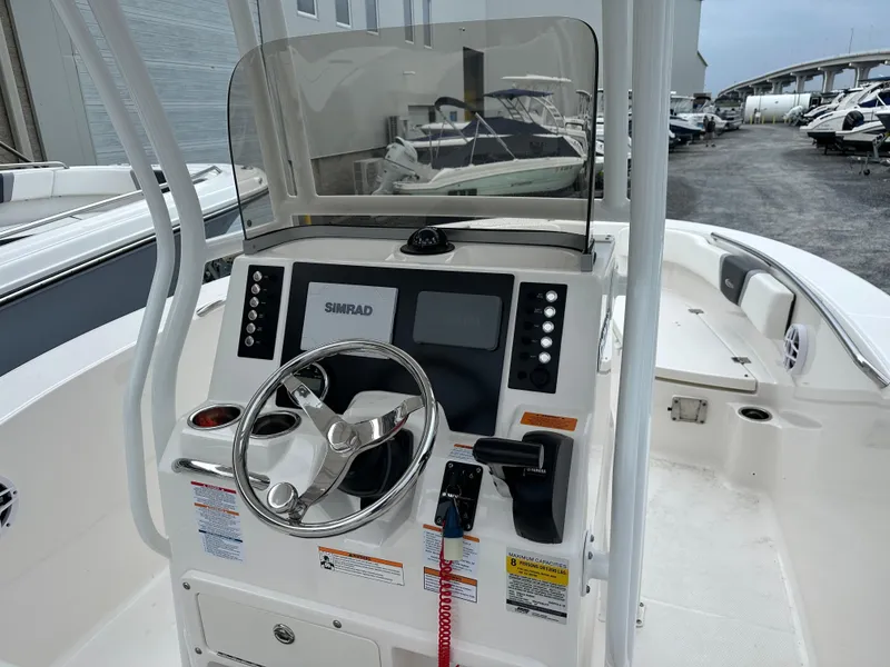 Slide: The Image of 2023 Robalo R200 Center Console boat dashboard with steering wheel and Simrad display. - 12