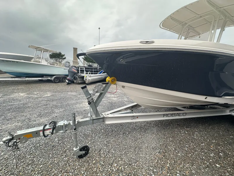Slide: The Image of 2023 Robalo R200 Center Console boat on trailer, parked on gravel lot. - 2