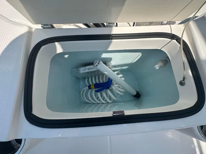 Slide: The Image of Livewell in 2023 Robalo R200 Center Console boat, featuring coiled hose and nozzle. - 23
