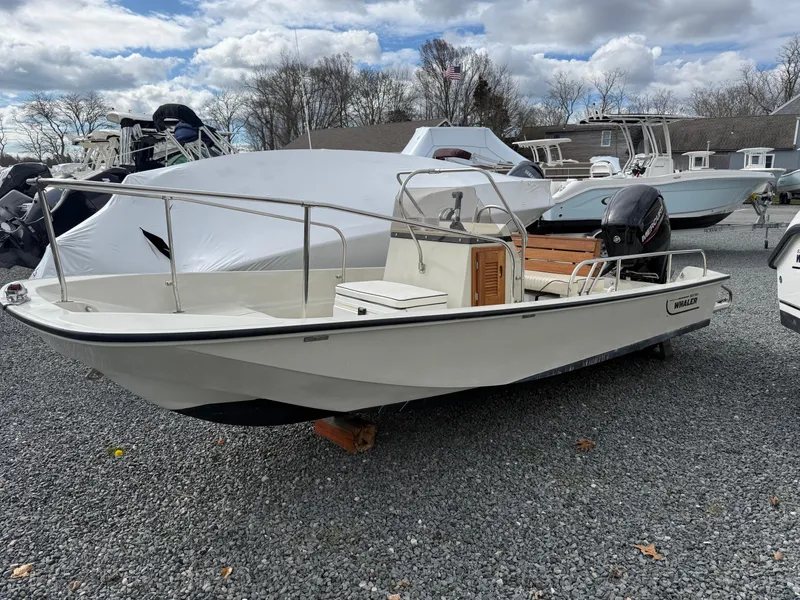 Slide: The Image of 1993 Boston Whaler Montauk 17 CC boat on gravel lot, under cloudy sky. - 0