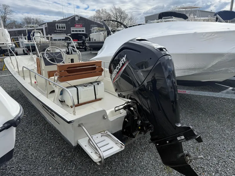 Slide: The Image of 1993 Boston Whaler Montauk 17 CC boat with Mercury outboard motor, parked on gravel. - 2