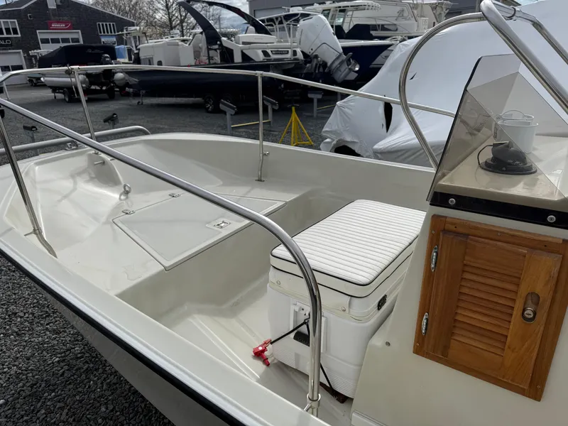 Slide: The Image of 1993 Boston Whaler Montauk 17 CC boat interior with console and seating, docked outdoors. - 5
