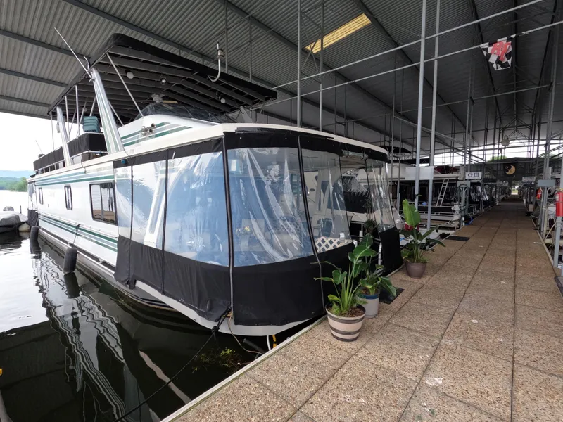 The Image of 1998 Jamestowner 1667WB Americana Custom houseboat docked in covered marina with potted plants. - 1