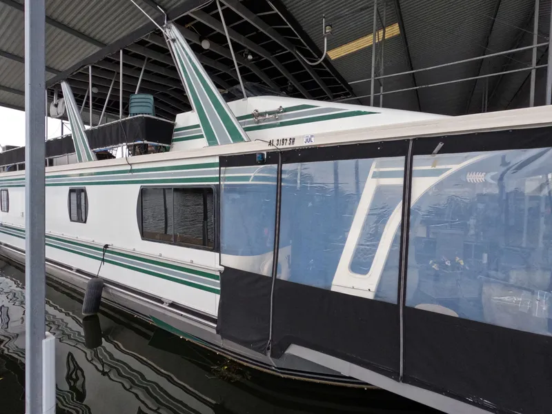 Slide: The Image of 1998 Jamestowner 1667WB Americana Custom houseboat docked under a covered marina. - 11