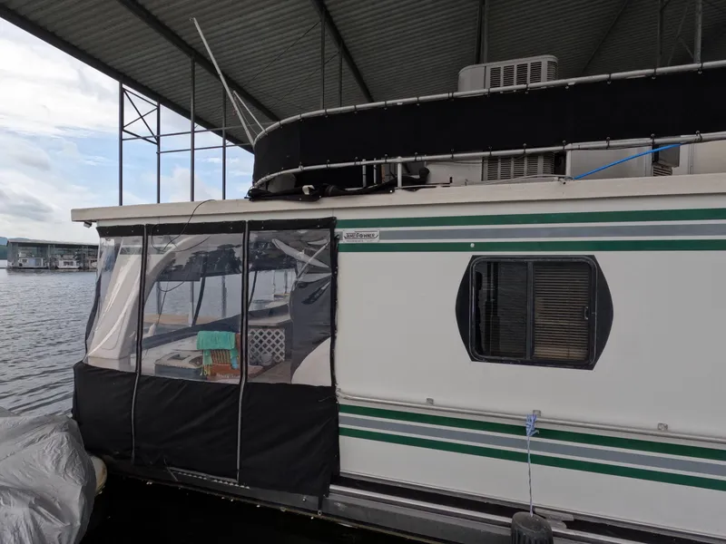 Slide: The Image of 1998 Jamestowner 1667WB Americana Custom houseboat docked under a covered marina. - 14