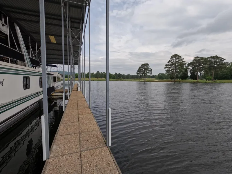Slide: The Image of Docked Jamestowner 1667WB Americana Custom houseboat on a serene lake with trees in the background. - 15