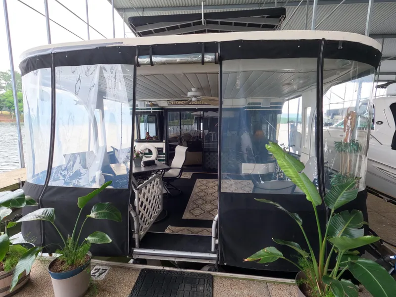 Slide: The Image of 1998 Jamestowner 1667WB Americana Custom houseboat with enclosed deck and potted plants. - 17