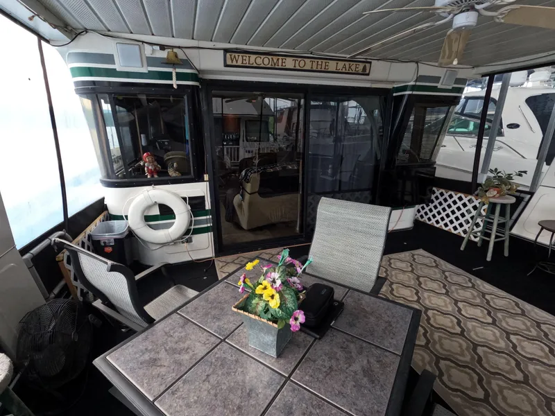 Slide: The Image of Houseboat interior with table, chairs, and decor, featuring a "Welcome to the Lake" sign. Jamestowner 1667WB Americana Custom, 1998. - 18