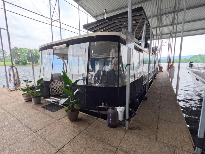 Slide: The Image of 1998 Jamestowner 1667WB Americana Custom houseboat docked with plants and covered deck. - 2