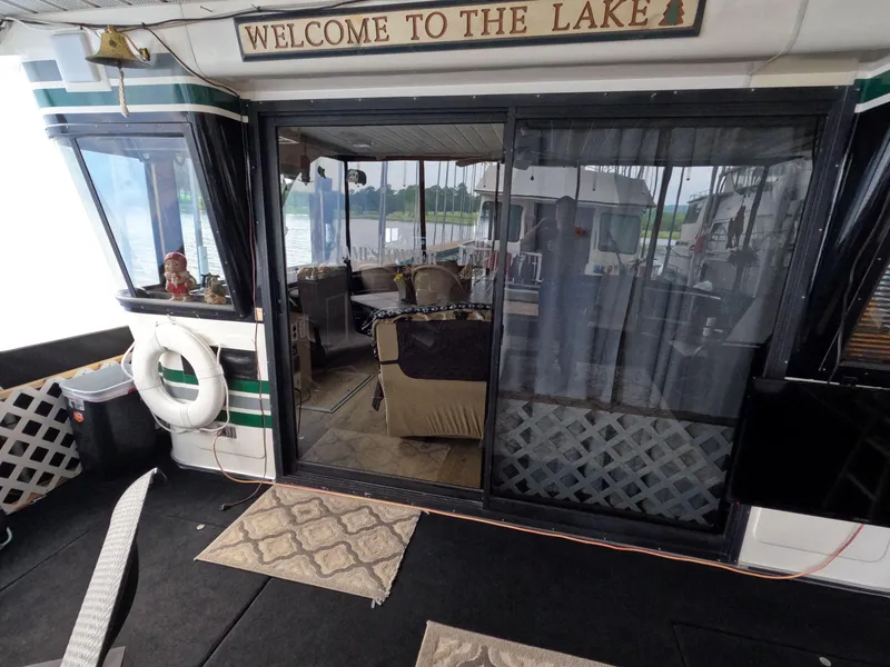Slide: The Image of Houseboat interior with "Welcome to the Lake" sign, featuring cozy seating and lake view. Jamestowner 1667WB Americana Custom, 1998. - 22