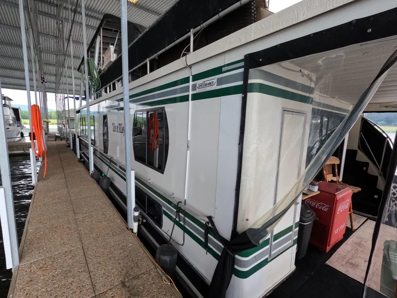 Slide: The Image of 1998 Jamestowner 1667WB Americana Custom houseboat docked under a covered marina. - 5