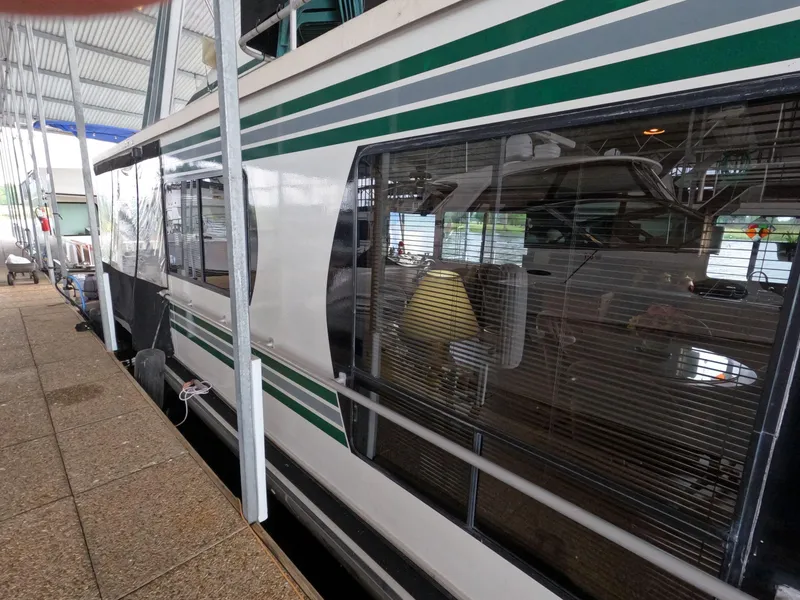 Slide: The Image of 1998 Jamestowner 1667WB Americana Custom houseboat docked under a covered marina. - 7