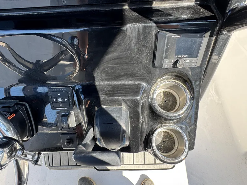 Slide: The Image of 2025 Tidewater 232 LXF boat dashboard with steering wheel, controls, and cup holders. - 15