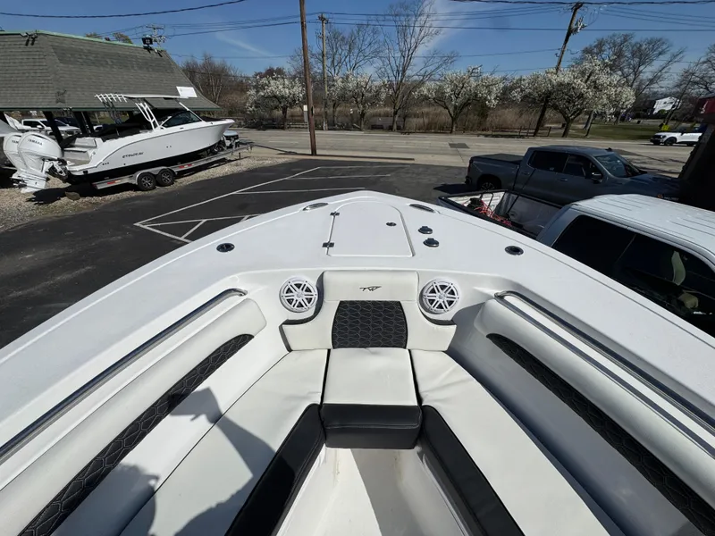 Slide: The Image of 2025 Tidewater 232 LXF boat interior with seating and speakers, parked outdoors. - 20