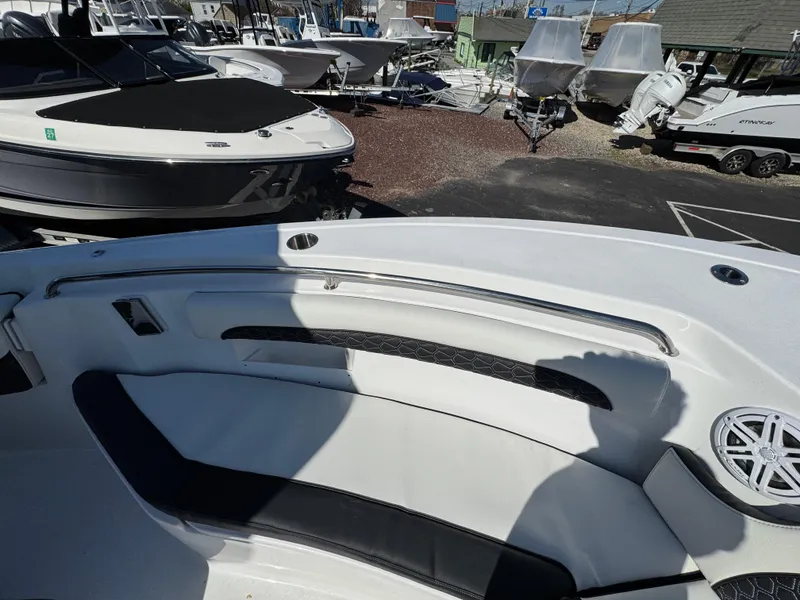 Slide: The Image of 2025 Tidewater 232 LXF boat interior with seating and speaker, in a marina setting. - 21