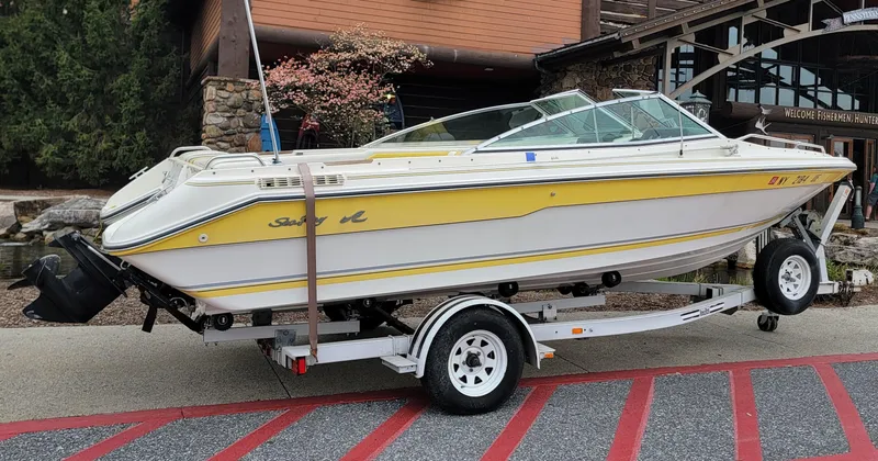 Slide: The Image of 1990 Sea Ray 200 BR boat on trailer, yellow and white, parked near a building. - 1