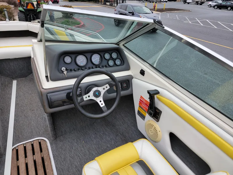Slide: The Image of 1990 Sea Ray 200 BR boat interior with steering wheel and dashboard, featuring yellow and white seating. - 11