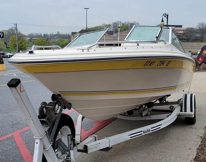 Slide: The Image of 1990 Sea Ray 200 BR boat on trailer, yellow and white, parked outdoors. - 16