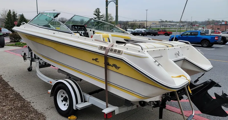 Slide: The Image of 1990 Sea Ray 200 BR boat on trailer, yellow and white design, parked outdoors. - 4