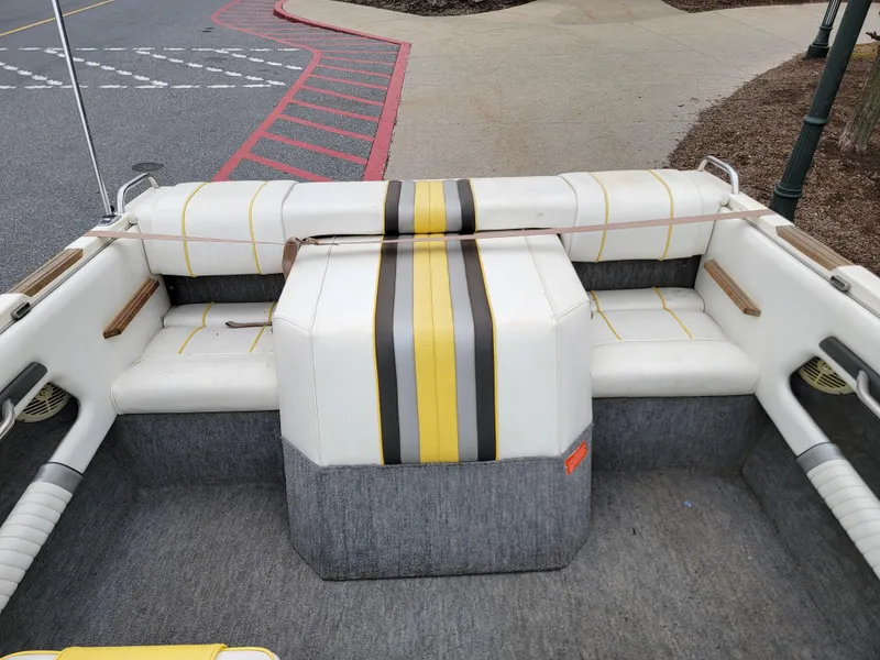 Slide: The Image of 1990 Sea Ray 200 BR boat interior with striped seating and carpeted flooring. - 8