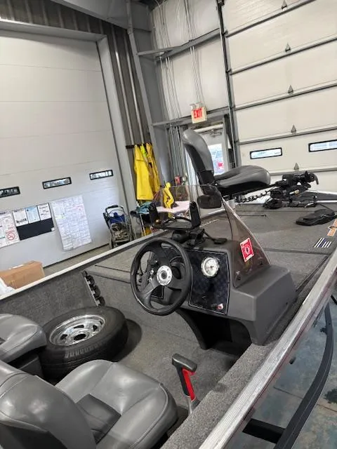 Slide: The Image of 2019 Bass Tracker Classic boat interior with steering wheel and seating in a garage. - 5