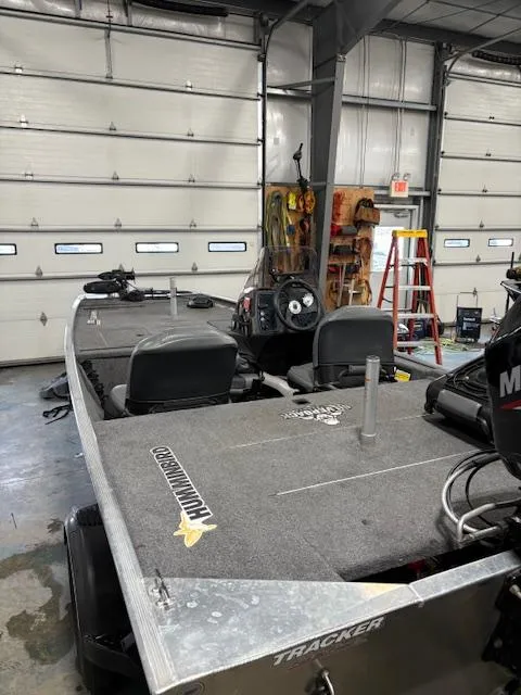 Slide: The Image of 2019 Bass Tracker Classic boat in a garage, featuring a spacious deck and steering console. - 8