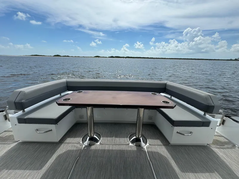 Slide: The Image of 2021 Cruisers Yachts 60 Cantius deck with seating and table, overlooking serene water. - 31