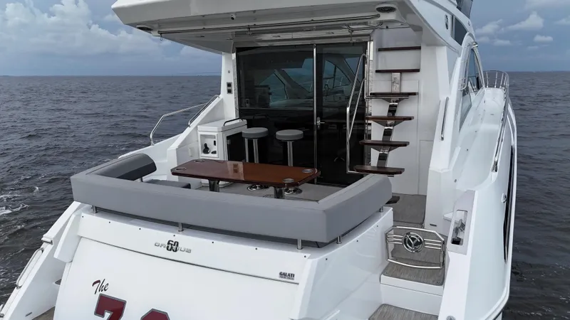 Slide: The Image of 2021 Cruisers Yachts 60 Cantius, luxury yacht with outdoor seating, ocean backdrop. - 34