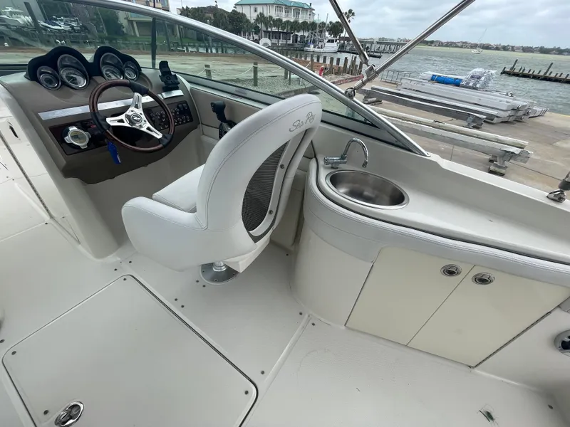 Slide: The Image of 2009 Sea Ray 260 Sundeck interior with helm, steering wheel, and sink, dockside view. - 15