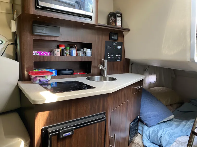 Slide: The Image of Compact kitchen and sleeping area inside a 2019 Regal 26 Express boat. - 12