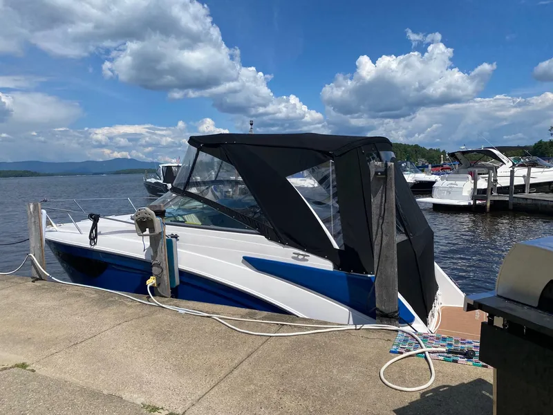 Slide: The Image of 2019 Regal 26 Express boat docked by a scenic lake under a partly cloudy sky. - 3