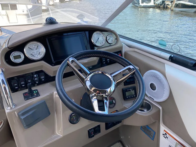Slide: The Image of 2019 Regal 26 Express boat helm with steering wheel and gauges, docked by the water. - 9