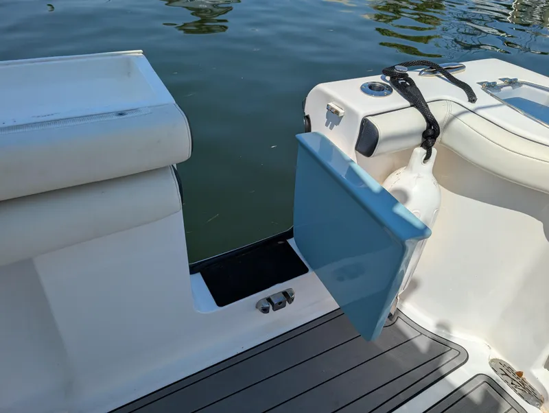 Slide: The Image of 2022 Tidewater 256 CC Adventure boat with open transom door, docked on calm water. - 21