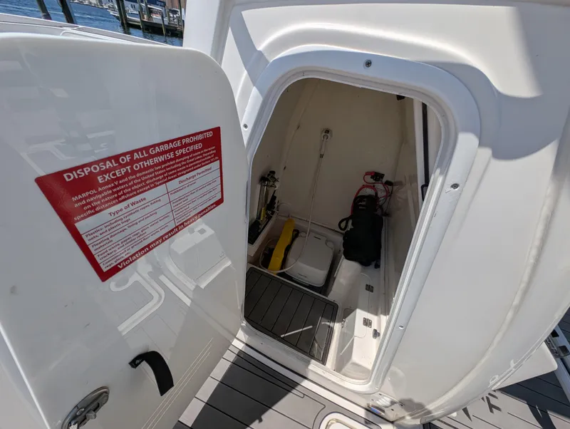 Slide: The Image of 2022 Tidewater 256 CC Adventure boat storage compartment with safety equipment and disposal notice. - 46