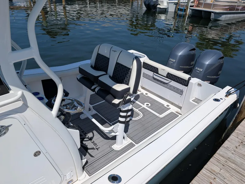 Slide: The Image of 2022 Tidewater 256 CC Adventure boat with dual engines, docked on calm water. - 6