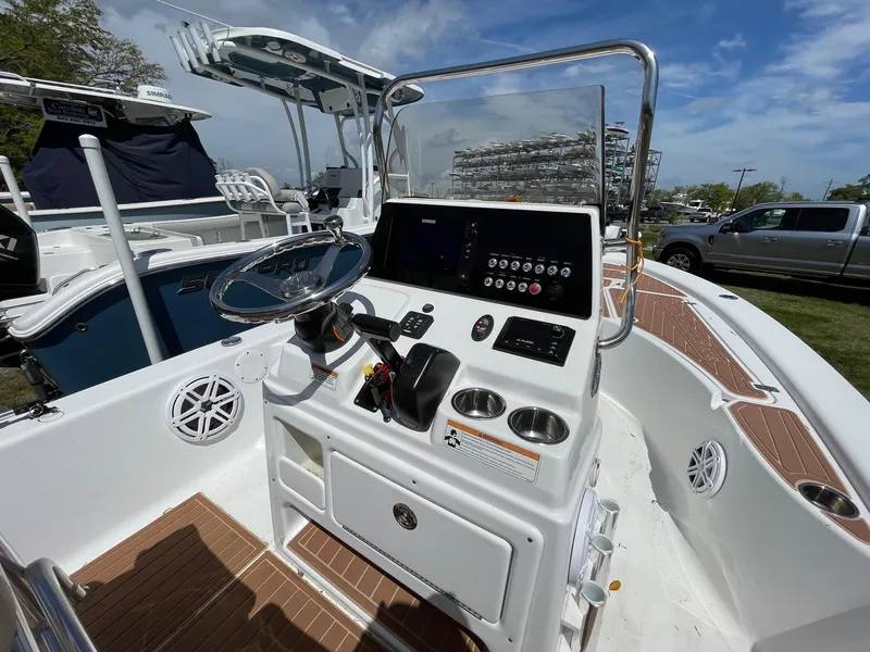 Slide: The Image of 2017 Sportsman Masters 207 Bay Boat console with steering wheel and controls, docked outdoors. - 8