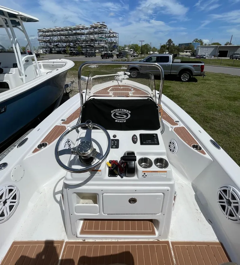 Slide: The Image of 2017 Sportsman Masters 207 Bay Boat with steering console and seating, docked under a clear sky. - 9