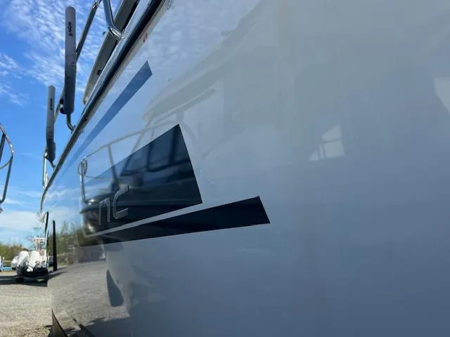 Slide: The Image of Side view of a 2020 Jeanneau NC 1095 Fly boat with sleek design and blue sky background. - 38