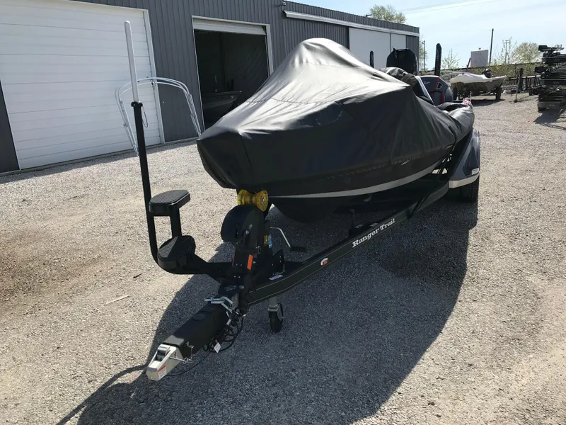 Slide: The Image of 2025 Lund 1875 Impact XS Sport boat covered on trailer, parked outdoors. - 10