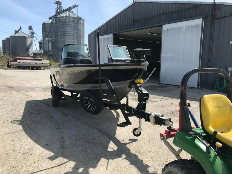 Slide: The Image of 2025 Lund 1875 Impact XS Sport boat on trailer near industrial buildings. - 11