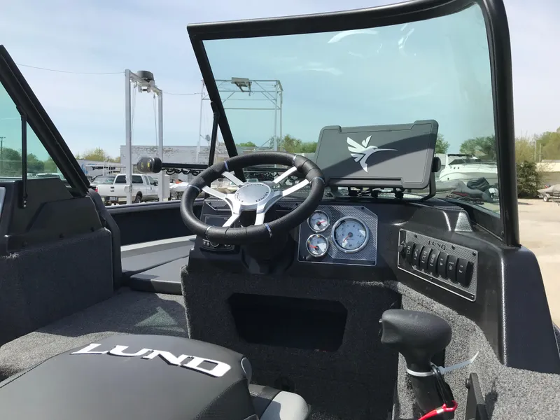 Slide: The Image of 2025 Lund 1875 Impact XS Sport boat interior with steering wheel and dashboard controls. - 23